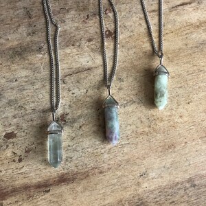 May include: Three silver chain necklaces with green, purple, and clear crystal point pendants.