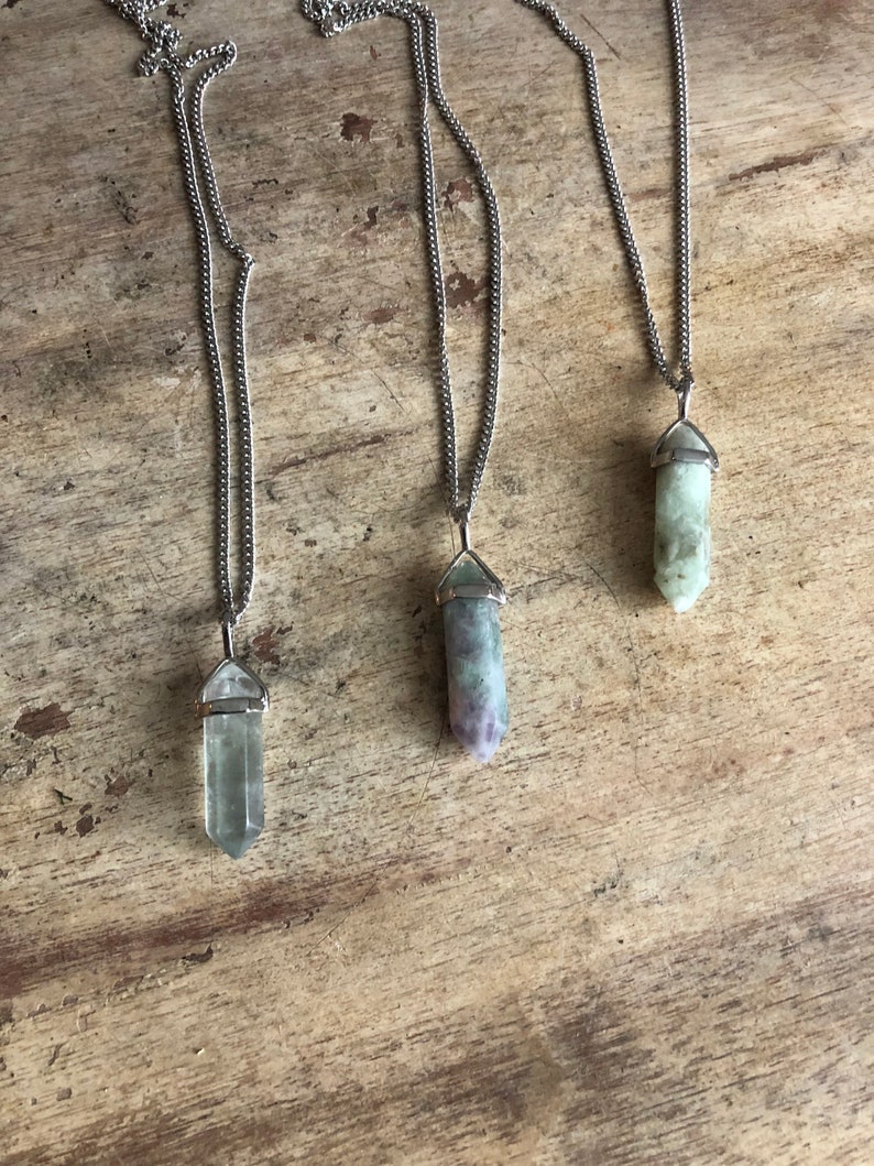 May include: Three silver chain necklaces with green, purple, and clear crystal point pendants.
