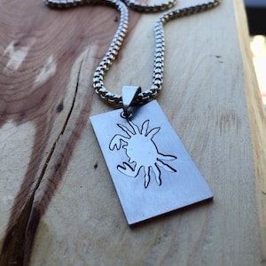 May include: A silver chain necklace with a rectangular pendant featuring a cutout design of a crab.