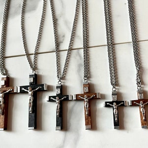 May include: Five silver chain necklaces with wooden crucifix pendants. The crucifixes are made of dark wood with a silver figure of Jesus Christ.