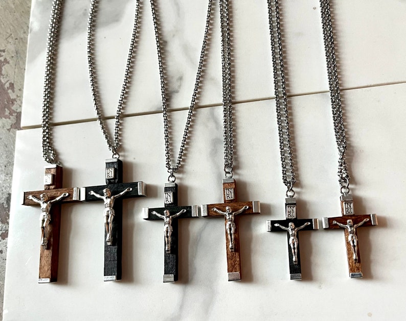 May include: Five silver chain necklaces with wooden crucifix pendants. The crucifixes are made of dark wood with a silver figure of Jesus Christ.