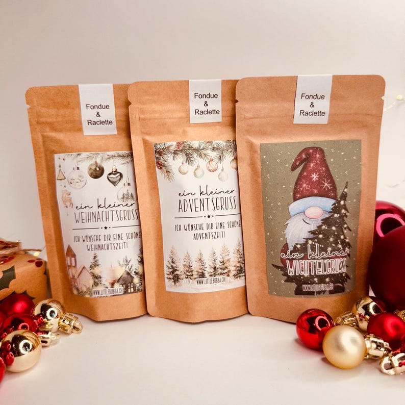 May include: Three brown paper pouches labelled "Fondue & Raclette" with festive designs. One features a gnome with a Christmas tree, another has a winter village scene, and the third displays a forest. Each pouch has German text.