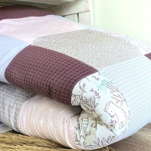 Könnte beinhalten: Ein Stapel gesteppter Kissenbezüge mit Patchwork-Muster. Die Bezüge zeigen verschiedene Muster, darunter geometrische Formen, Punkte und eine Waldszene mit einem Bären.