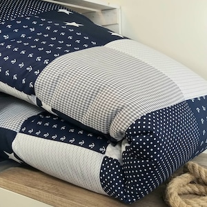 May include: A blue and white patchwork quilt with a nautical theme. The quilt features anchors, stars, and polka dots.