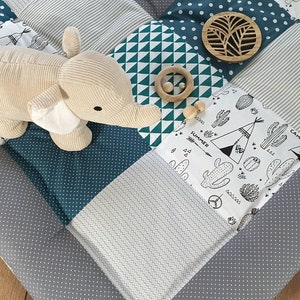 Könnte beinhalten: Eine graue und weiße Spielmatte mit einem grünen, weißen und schwarzen geometrischen Muster. Die Matte zeigt ein Stofftier-Elefant, ein Holz-Tipi und einen Holzring mit Perlen. Die Matte hat die Wörter "Summer" und "Camp" aufgedruckt.