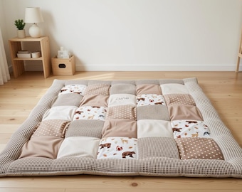 Op de afbeelding: Een rechthoekige patchwork vloermat met een raster van vierkanten in beige, witte en bruine tinten. De stoffen vierkanten wisselen af tussen effen kleuren, stippen, kleine ruitpatronen en een print van bosdieren en bladeren.