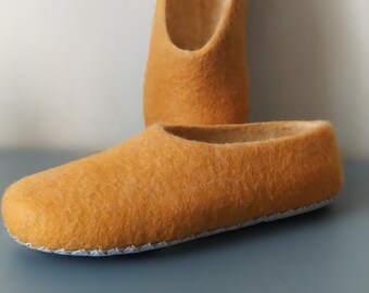 May include: A pair of mustard yellow wool slippers with a white stitched edge.