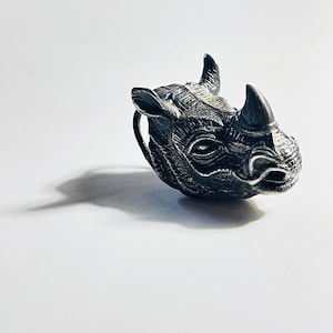 Può includere: Una scultura in argento di testa di rinoceronte con una superficie dettagliata e testurizzata.