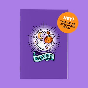 May include: A purple notebook featuring a central illustration of a crystal ball containing a ghost, a pumpkin, a crescent moon, and stars. Below the crystal ball is a banner with the text NOTES. An orange circle contains the text HEY! THIS HAS 48 LINED PAGES INSIDE.