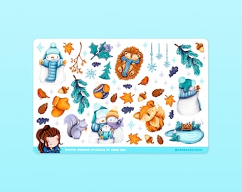 Könnte beinhalten: Eine Blatt mit winterlichen Stickern mit einer Vielzahl von niedlichen Figuren und Objekten, darunter ein Schneemann, ein Pinguin, ein Igel, ein Fuchs, ein Eichhörnchen und eine Hütte. Die Sticker sind im Aquarellstil mit weißem Hintergrund und blauen, braunen und orangen Akzenten illustriert. Der Text "WINTER WONDER STICKERS BY ANNA RAZ" befindet sich am unteren Rand des Blattes.