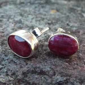 Peut inclure: Une paire de boucles d'oreilles en argent avec des pierres pr&eacute;cieuses en rubis rouge. Les boucles d'oreilles sont de forme ovale et ont une finition lisse et polie.