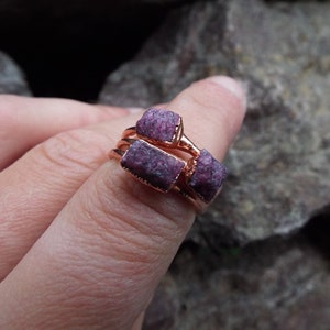May include: A ring with three raw ruby stones set in rose gold.