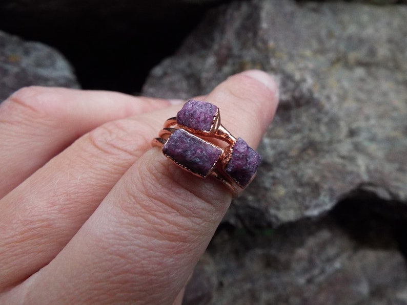 May include: A ring with three raw ruby stones set in rose gold.