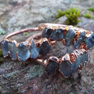 Könnte beinhalten: Drei Ringe aus Roségold mit rohen Aquamarin-Steinen, die in die Band gefasst sind. Die Ringe sind übereinander gestapelt.