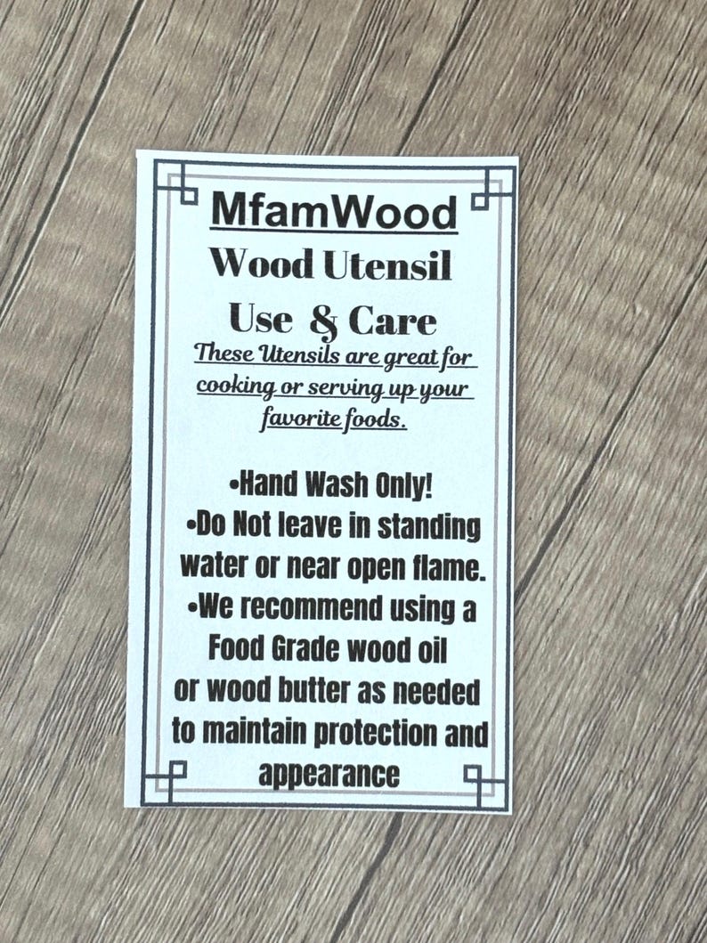 Puede incluir: Una tarjeta rectangular blanca con texto negro sobre una superficie de madera. La tarjeta dice "MfamWood Wood Utensil Use & Care" y proporciona instrucciones de cuidado para utensilios de madera, incluyendo lavado a mano y recomendaciones de aceite.