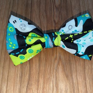 May include: A black bow tie with a green, blue, and white geometric pattern.