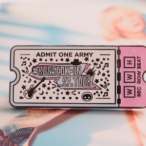 Puede incluir: Pin rectangular con forma de entrada, con el texto "ADMIT ONE ARMY" y "#RUNSEOKJIN EP. TOUR". El pin presenta una guitarra, notas musicales, estrellas y un sombrero. La entrada tiene un borde rosa.