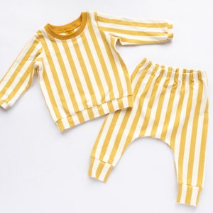 May include: A yellow and white striped baby outfit with a long-sleeved shirt and matching pants.