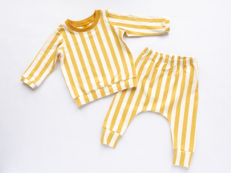 May include: A yellow and white striped baby outfit with a long-sleeved shirt and matching pants.
