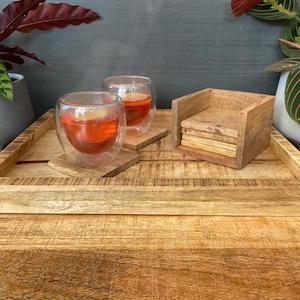 May include: A wooden tray with a natural finish, featuring two glass cups of tea and a set of wooden coasters. The tray is made of solid wood and has a rustic look.