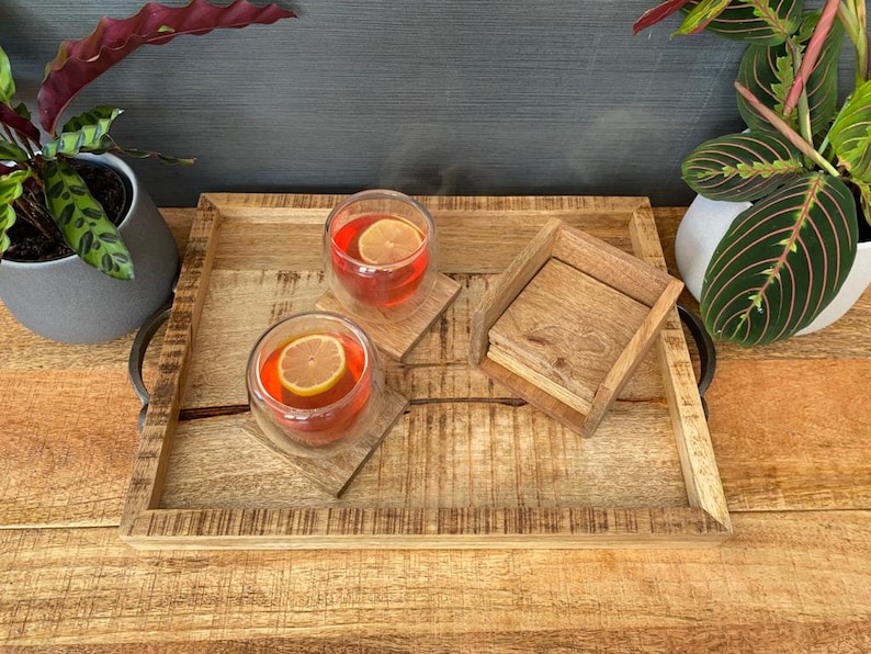 May include: A wooden serving tray with two glasses of red liquid and lemon slices. The tray has a natural wood finish and is decorated with a distressed look. There are also two wooden coasters on the tray.