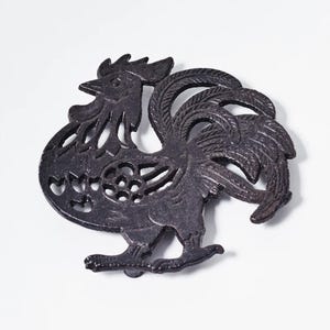 May include: Black cast iron hot pad shaped like a rooster with a cut-out design.