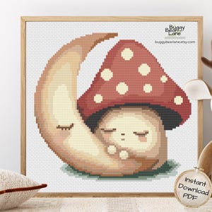 May include: Cross-stitch art of a sleeping mushroom and moon. The mushroom has a red cap with white spots. The moon is a light peach color. The artwork is in a wooden frame. The text "Buggy Beary Lane" is in the top right corner.