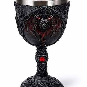 May include: A decorative goblet featuring a dark, textured exterior with a sculpted winged demon figure in black and red. The stem includes a circular red gemstone accent, and the interior is lined with a smooth, polished silver-tone metal finish.