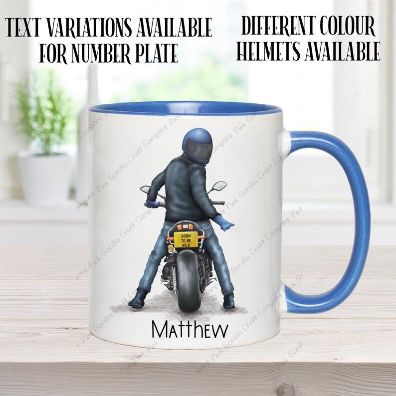May include: A white ceramic mug with a blue rim and handle. The mug features a graphic of a person riding a motorcycle with the text "Born to be Wild" on the license plate. The name "Matthew" is printed below the graphic.