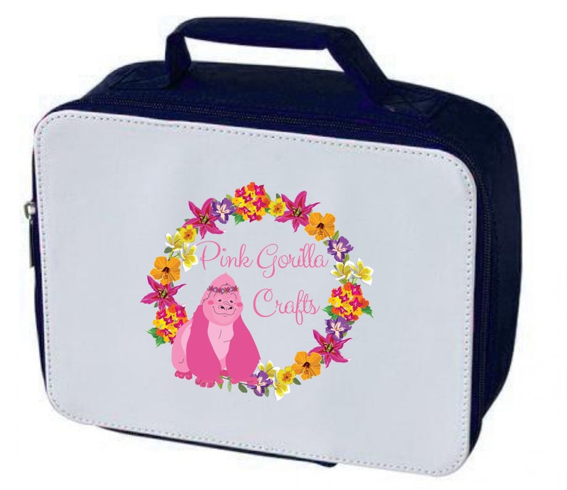 Pode incluir: Uma bolsa de almo&ccedil;o branca com um z&iacute;per e uma al&ccedil;a azul marinho. A bolsa apresenta um gorila rosa usando uma coroa de flores cercada por uma guirlanda de flores coloridas. O texto "Pink Gorilla Crafts" est&aacute; impresso na bolsa.