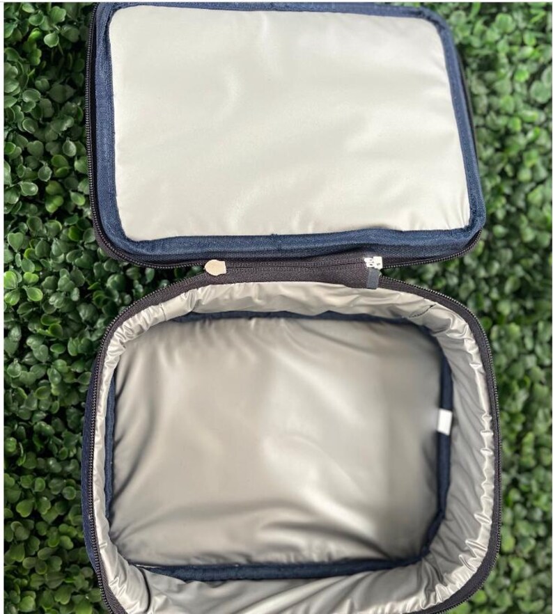 Pode incluir: Uma bolsa de almo&ccedil;o isolada preta com fecho de correr. A bolsa est&aacute; aberta e o interior &eacute; forrado com um material prateado.