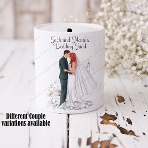 May include: White ceramic money jar with a slot on top. The jar features a graphic of a bride and groom kissing. The text on the jar reads "Jack and Marie's Wedding Fund".