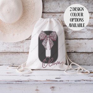 May include: A white drawstring bag with a black oval design featuring a pink leopard print bow and the name "Olivia" in cursive. The text "2 DESIGN COLOUR OPTIONS AVAILABLE" is in a white circle. A straw hat is in the background.