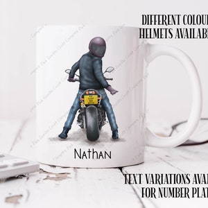 May include: White ceramic mug with a graphic of a person riding a motorcycle. The motorcycle has a yellow license plate that reads "EAT SLEEP RIDE REPEAT". The mug has a black handle and the name "Nathan" is printed on the bottom. The text "DIFFERENT COLOUR HELMETS AVAILABLE" is printed above the image and the text "TEXT VARIATIONS AVAILABLE FOR NUMBER PLATE" is printed below the image.