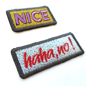 May include: Two embroidered patches. One has the word "NICE" in purple on a yellow background, with a black border. The other patch says "haha, no!" in red on a light blue background, with a black border.