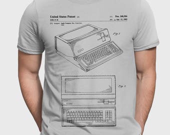 Puede incluir: Una camiseta gris con una ilustración en blanco y negro de un diseño de patente de computadora Apple vintage. El número de patente es Des. 268,584 y la fecha es el 12 de abril de 1963. El texto "United States Patent" también está incluido en el diseño.