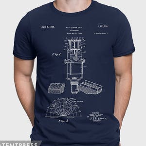 Puede incluir: Una camiseta azul marino con una impresión blanca de un diseño de patente de micrófono. El número de patente es 2.113.219 y la fecha de la patente es el 5 de abril de 1938. La patente es para un micrófono inventado por H.F. Olson et al. y presentada el 31 de mayo de 1934.