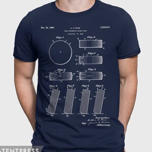May include: A navy blue t-shirt with a white print of a patent drawing for a "Roll-Preventing Hockey Puck". The patent number is 2,226,516 and the date is December 24, 1940. The drawing shows different views of the puck.