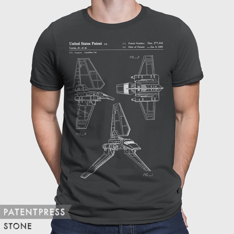 May include: A dark gray t-shirt with a white outline of a spaceship design. The design includes the text "United States Patent", "Lucas, Jr. et al.", "Patent Number: Des. 277,116", and "Date of Patent: Jan. 5, 1955".