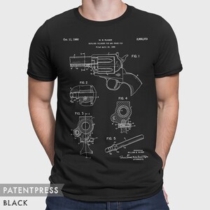 Puede incluir: Camiseta negra con una impresi&oacute;n blanca de un dibujo de patente para un pasador de cilindro de rev&oacute;lver y un pasador transversal. El n&uacute;mero de patente es 2.955.373 y la fecha es el 11 de octubre de 1960. El dibujo muestra las diferentes partes del rev&oacute;lver e incluye el texto "W. B. RUGER" y "REVOLVER CYLINDER PIN AND CROSS PIN".