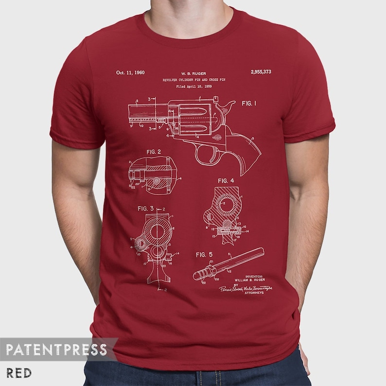 Puede incluir: Una camiseta roja con una impresi&oacute;n blanca de un dibujo de patente para un pasador de cilindro de rev&oacute;lver y un pasador transversal. El n&uacute;mero de patente es 2.955.373 y la fecha es el 11 de octubre de 1960. El inventor es William B. Ruger.