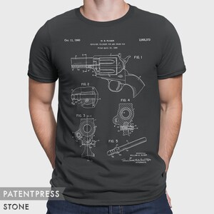 Puede incluir: Una camiseta negra con una impresi&oacute;n blanca de un dibujo de patente para un pasador de cilindro de rev&oacute;lver y un pasador transversal. El n&uacute;mero de patente es 2.955.373 y la fecha es el 11 de octubre de 1960. El inventor es William B. Ruger.