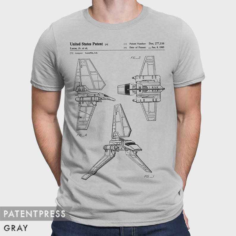 May include: A gray t-shirt with a black and white illustration of a spaceship patent design. The text on the shirt reads "United States Patent Lucas, Jr. et al. Patent Number: Des. 277,116. Date of Patent: Jan. 5, 1985. FIG. 2 FIG. 1"