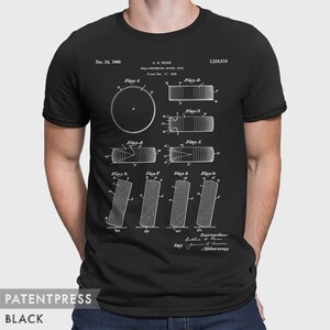 May include: A black t-shirt with a white print of a patent for a "Ball-Preventing Hockey Puck" by A.H. Ross, filed February 17, 1940. The patent number is 2,226,516. The patent drawing shows different views of the puck.