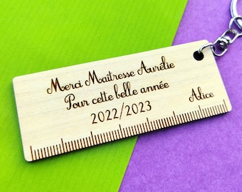 May include: A wooden ruler keychain with the text "Merci Maitresse Aurelie Pour cette belle année 2022/2023" and the name "Alice" engraved on it.