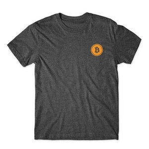 May include: A dark gray t-shirt with a small orange circle on the left chest featuring a black Bitcoin symbol.