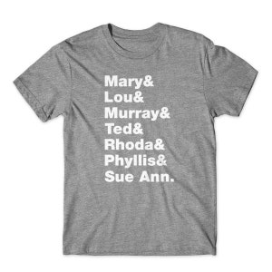 May include: A heather grey t-shirt with white text that reads "Mary & Lou & Murray & Ted & Rhoda & Phyllis & Sue Ann."