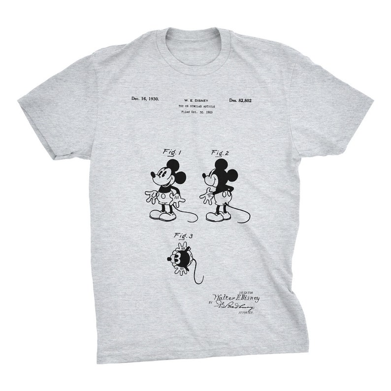 K&ouml;nnte beinhalten: Ein graues T-Shirt mit einem Schwarzwei&szlig;bild von Mickey Mouse aus einer Patentzeichnung. Die Zeichnung zeigt Mickey Mouse in drei verschiedenen Posen. Der Text auf dem T-Shirt lautet "Dec. 16, 1930. W.E. Disney Des. 82,802 Tot of Similar Article Filed Oct. 20, 1930. Fig. 1 Fig. 2 Fig. 3 Inventor Walter E. Disney By Fred  Harman Attorney".