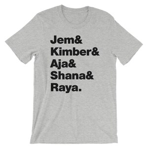 May include: Grey t-shirt with black text that reads "Jem & Kimber & Aja & Shana & Raya."