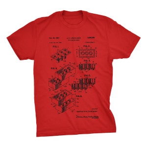 K&ouml;nnte beinhalten: Ein rotes T-Shirt mit einem schwarz-wei&szlig;en Bild einer Patentzeichnung f&uuml;r einen Baustein. Die Patentzeichnung zeigt sechs verschiedene Ansichten des Bausteins und enth&auml;lt den Text "Oct. 24, 1961", "GK CHRISTIANSEN", "3,005,282", "FIG. 1", "FIG. 2", "FIG. 3", "FIG. 4", "FIG. 5", "FIG. 6", "INVENTOR", "Godtfred Kirk Christiansen".